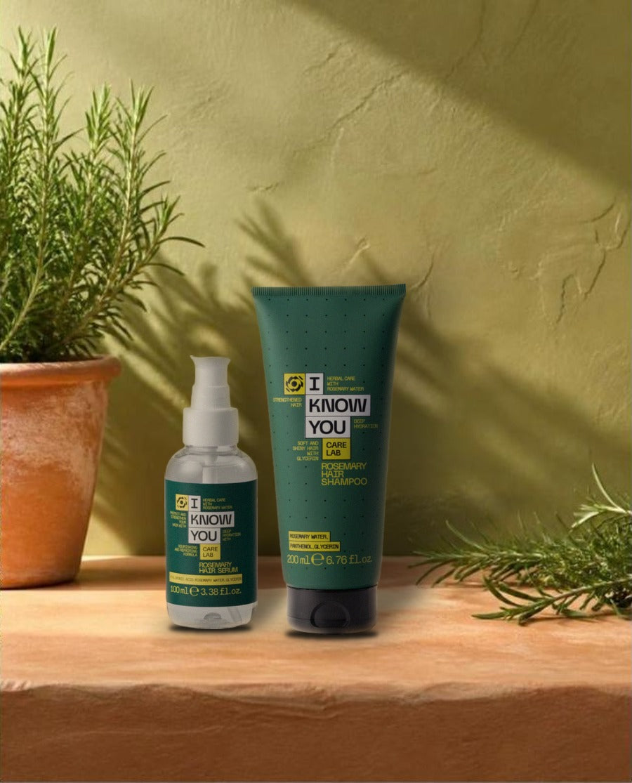 Champú y sérum capilar de romero junto a una planta de romero al sol